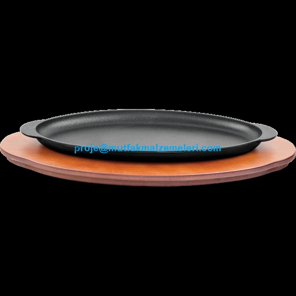 Ahşap nihale üzerinde sergilenen, 30x16 cm ölçülerinde, oval formlu, kulplu ve düz tabanlı siyah döküm demir alabalık ve fajita sunum tavası. Isıyı hapseden profesyonel restoran tipi döküm servis ekipmanı.